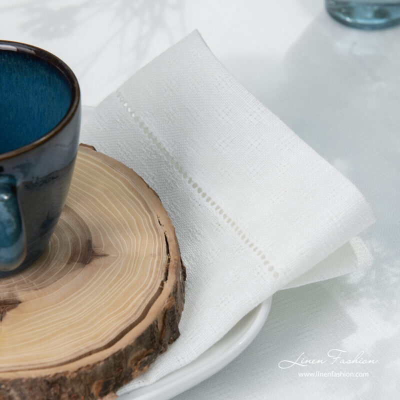 Border of white patterned linen napkin with hemstitch