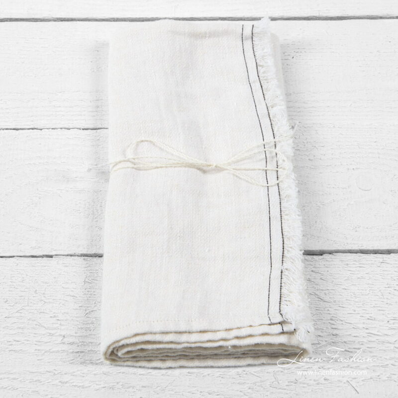 White kitchen towel with brown stitches and loose fringes on one side
