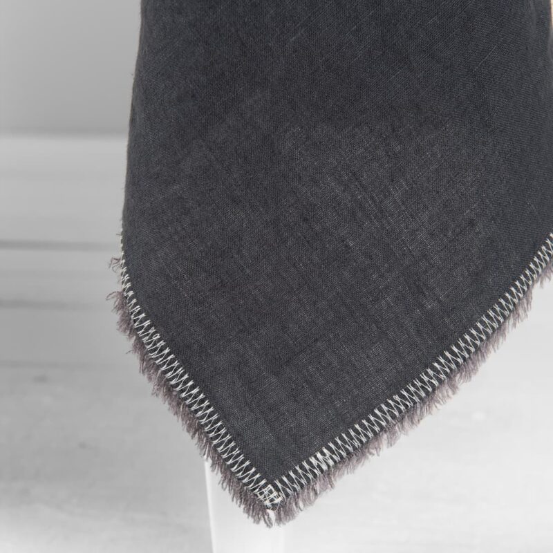 linen grey tablecloth with decorative seam and loose fringes.