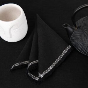 black linen napkin with decorative stitch, loose fringes.