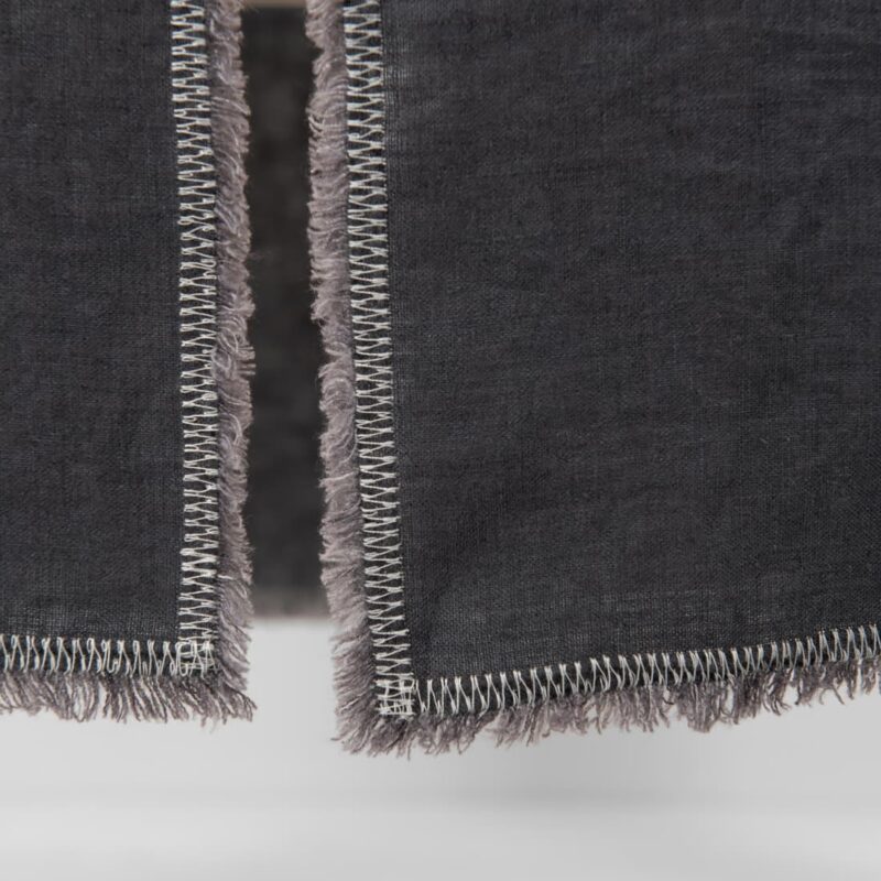 grey linen runner with decorative stitch with loose fringes.
