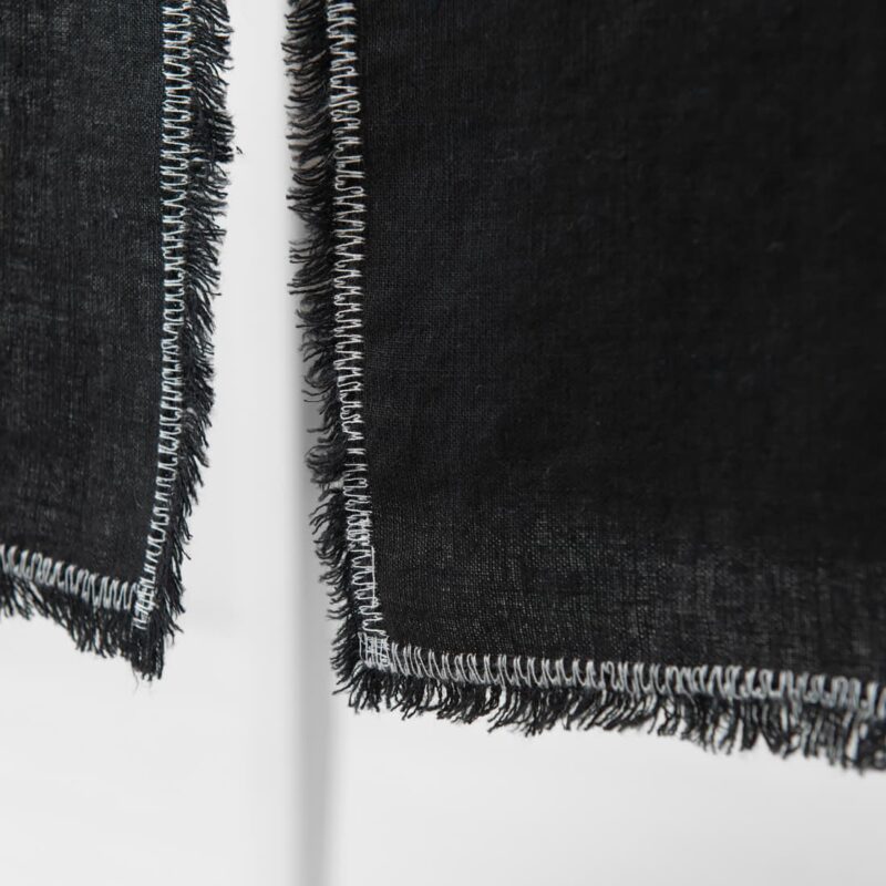 black linen runner with decorative stitch, loose fringes.