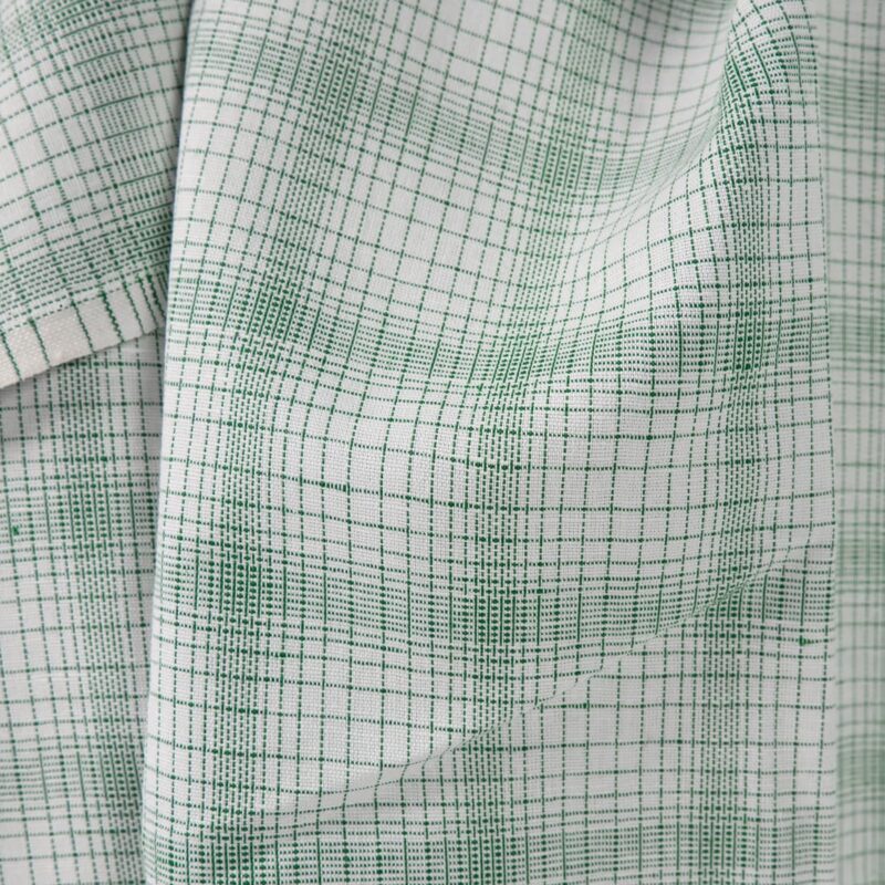 White linen cotton fabric with striped green checks close up view of pattern